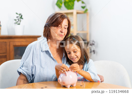 Granddaughter inserting coin in piggy bank with Granddaughter inserting coin in piggy bank with 119134668
