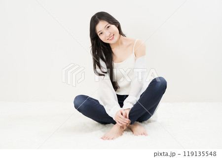 スキニージーンズ・ジーパン・デニムパンツをはいて胡座をかいて座る若い女性 119135548