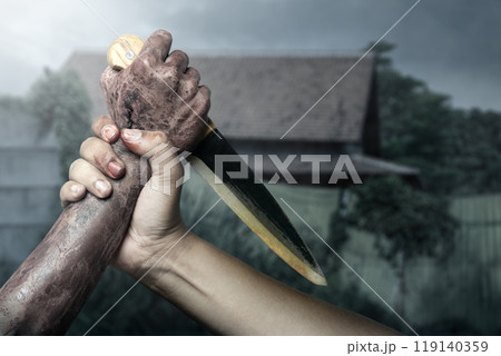 Zombie hand with bloody wound fighting with man on midnight background. Zombie hand holding knife is pointed at the man hand, creating tense and dangerous atmosphere 119140359