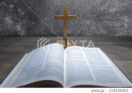 Wooden religion cross and opened blue book of Holy Bible. It is laying on a wooden table. Religious christian holiday. Symbol of faith in God, Christianity Feast 119140401