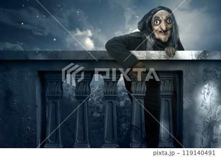 Old witch rising out behind balustrade with moonlight background. Scene is scary and creepy Old witch rising out behind balustrade with moonlight background. Scene is scary and creepy 119140491
