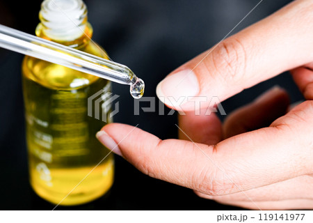 hands of a beautiful woman Dropping serum collagen moisturizer of face into clear gold bottle soft light background. Protector skin Treatment facial essence oil, Vitamin C. Beauty and spa Concept hands of a beautiful woman Dropping serum collagen moisturizer of face into clear gold bottle soft light background. Protector skin Treatment facial essence oil, Vitamin C. Beauty and spa Concept 119141977