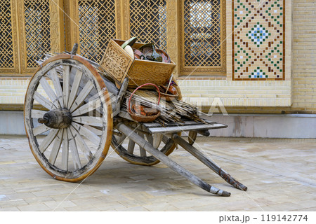 Old wooden cart with jugs and wicker baskets next to a brick house with Uzbek ornaments in Samarkand Old wooden cart with jugs and wicker baskets next to a brick house with Uzbek ornaments in Samarkand 119142774