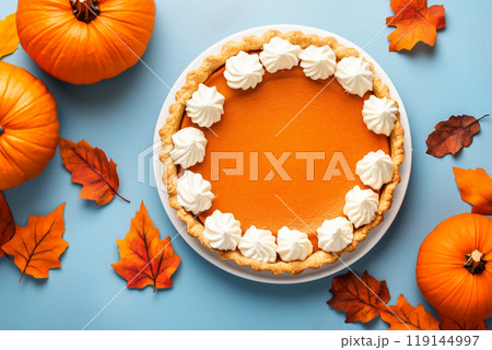Closeup of pumpkin pie with dollops of whipped cream and sprinkle of cinnamon on white plate and fall holiday background Closeup of pumpkin pie with dollops of whipped cream and sprinkle of cinnamon on white plate and fall holiday background 119144997