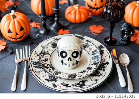 Halloween themed table setting with skulls, black pumpkins, and ornate cutlery. Concept of spooky dining decor 119145035