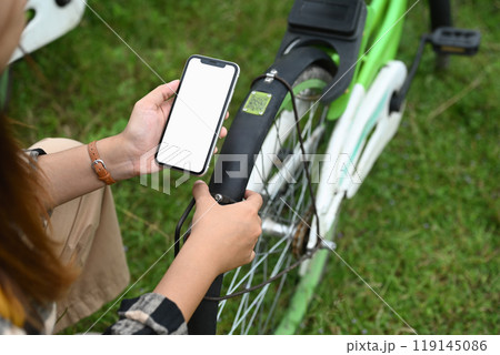 Young woman using her mobile phone to unlocked bike at the bicycle rental station Young woman using her mobile phone to unlocked bike at the bicycle rental station 119145086