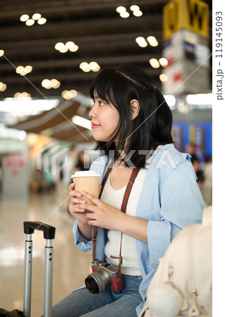 Young woman with a coffee cup waiting for her flight at the airport 119145093