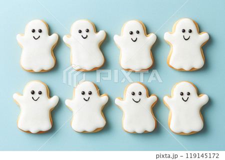 Halloween ghost shaped cookies decorated with white icing and black icing faces, arranged on plain background. Halloween ghost shaped cookies decorated with white icing and black icing faces, arranged on plain background. 119145172