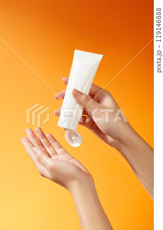 Image templates for skincare ads show a white, label-free tube that is grasped firmly in the hand and is unbranded. The orange backdrop creates a striking contrast, signifying brightness and energy. Image templates for skincare ads show a white, label-free tube that is grasped firmly in the hand and is unbranded. The orange backdrop creates a striking contrast, signifying brightness and energy. 119146888
