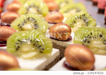 Cakes decorated with kiwi slices and nuts in sugar glaze. Sweet dessert. Close-up. 119147810