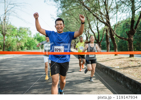 asian male athlete running towards finish line asian male athlete running towards finish line 119147934