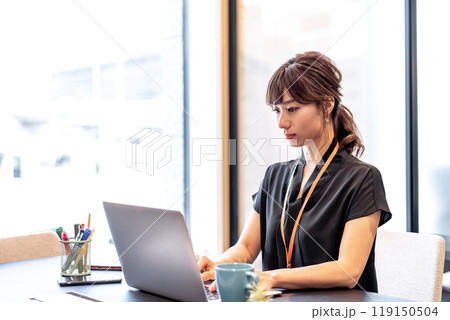 真剣な表情でパソコン作業をする女性 119150504