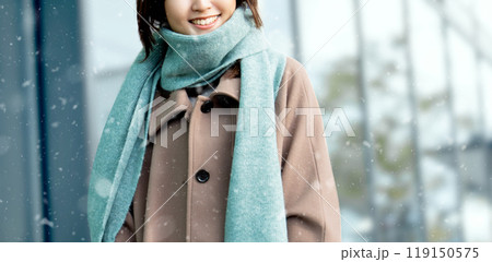 雪の降るオフィス街を歩く笑顔の女性 119150575