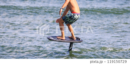 Man riding on a kite board hydrofoiling in the Atlantic Ocean 119150729