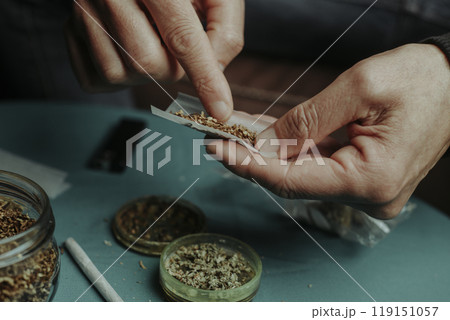 puts some tobacco on a rolling paper to make a joint 119151057