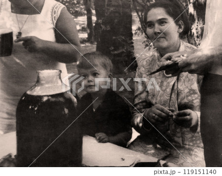 Vintage portrait of a boy and his mother at a table in a large glass jar with beer. Retro photo from 1970 Vintage portrait of a boy and his mother at a table in a large glass jar with beer. Retro photo from 1970 119151140