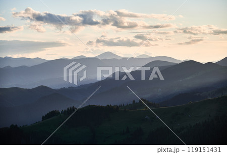 Soft blue hues of layered mountain ranges stretch into the distance under evening sky, creating tranquil and atmospheric landscape filled with gentle gradients and sense of vastness. Soft blue hues of layered mountain ranges stretch into the distance under evening sky, creating tranquil and atmospheric landscape filled with gentle gradients and sense of vastness. 119151431