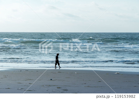 早朝の海岸を散歩する女性のシルエット 119153982