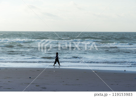 早朝の海岸を散歩する女性のシルエット 119153983