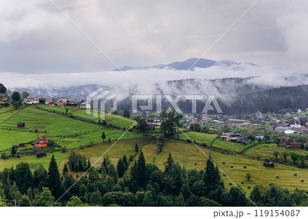 Misty morning in Vorokhta village with scenic view of Carpathian hills and fog-covered mountains 119154087