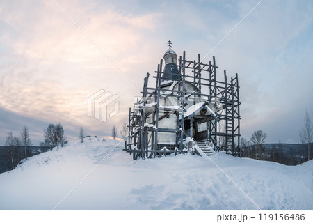 Old church in scaffolding. All covered with snow. 119156486