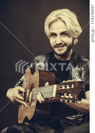 Blonde man playing acoustic guitar 119156997
