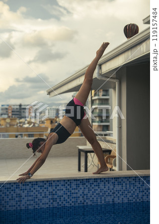 An Elegant and Graceful Diver Performing Acrobatic Moves at a Stunning Rooftop Pool 119157484