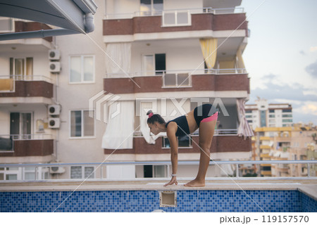 A Young Girl Eagerly Preparing to Dive Gracefully into a Bright Swimming Pool of Water A Young Girl Eagerly Preparing to Dive Gracefully into a Bright Swimming Pool of Water 119157570