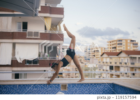 A Dynamic Acrobat Gracefully Performing a Handstand by the Relaxing Poolside Area A Dynamic Acrobat Gracefully Performing a Handstand by the Relaxing Poolside Area 119157594