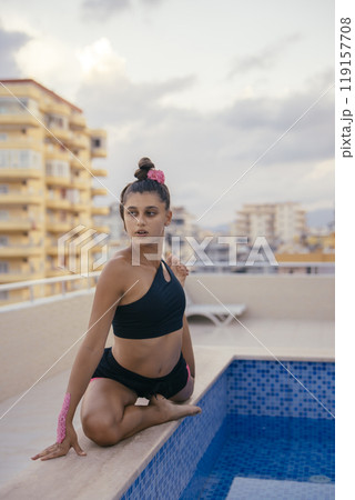 A Graceful and Young Dancer is Posing Elegantly by a Beautiful Rooftop Pool Area A Graceful and Young Dancer is Posing Elegantly by a Beautiful Rooftop Pool Area 119157708