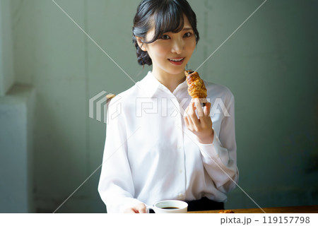 朝の落ち着いた雰囲気の中で一杯のコーヒーを飲む若い女性 119157798