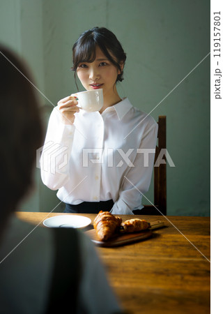朝の落ち着いた雰囲気の中で一杯のコーヒーを飲む若い女性 119157801