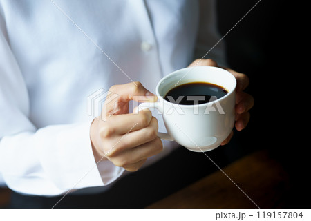 朝の落ち着いた雰囲気の中で一杯のコーヒーを飲む若い女性 119157804