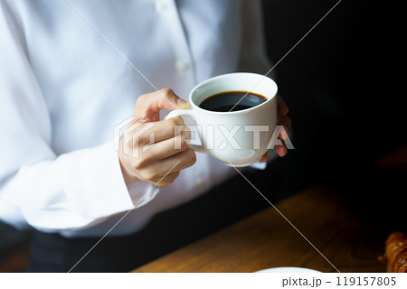 朝の落ち着いた雰囲気の中で一杯のコーヒーを飲む若い女性 119157805