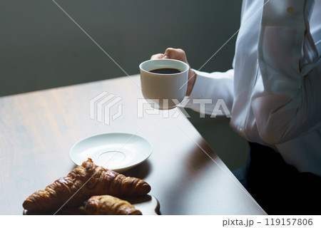 朝の落ち着いた雰囲気の中で一杯のコーヒーを飲む若い女性 119157806