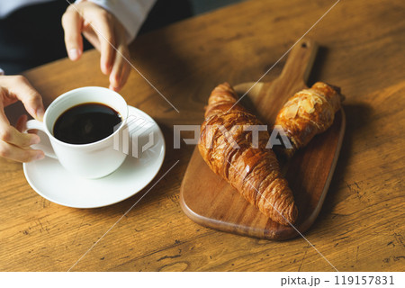 朝の落ち着いた雰囲気の中で一杯のコーヒーを飲む若い女性 119157831