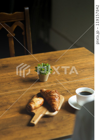 朝の落ち着いた雰囲気の中で一杯のコーヒーを飲む若い女性 119157842