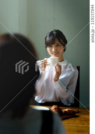 朝の落ち着いた雰囲気の中で一杯のコーヒーを飲む若い女性 119157844