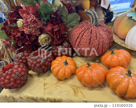 an autumn-themed arrangement featuring small orange pumpkins, red textured candles, and a floral centerpiece 119160310