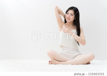 ビューティー　胡座をかいて脇の下を気にしている若い女性　脱毛　 119163331