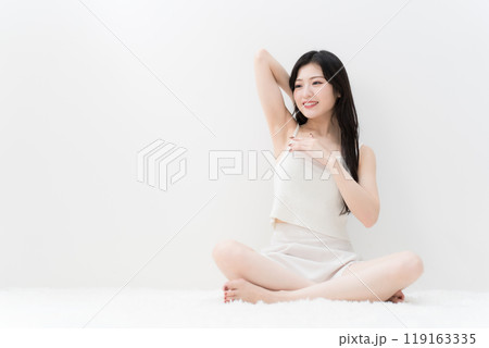 ビューティー　胡座をかいて脇の下を気にしている若い女性　脱毛　 119163335