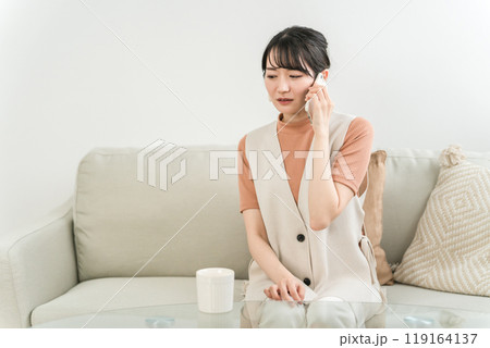 家でスマホを使って会話しながら悲しい・ショック・ストレスを抱えるアジア人女性 家でスマホを使って会話しながら悲しい・ショック・ストレスを抱えるアジア人女性 119164137