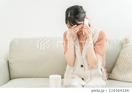 スマホで通話しながらショックを受けるアジア人女性（いじめ・トラブル・失恋） 119164139