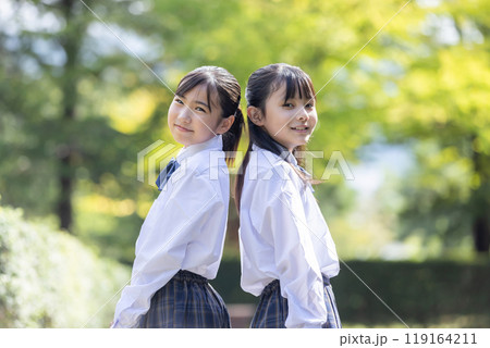 背中を合わせて微笑む小学生 119164211