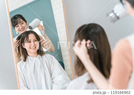 美容室・ヘアサロンでドライヤーで髪を乾かす・ブローしてもらうアジア人女性 美容室・ヘアサロンでドライヤーで髪を乾かす・ブローしてもらうアジア人女性 119166902