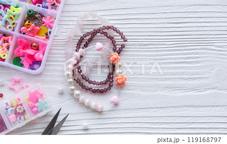 Colorful beaded bracelets and crafting supplies arranged on a white wooden table Colorful beaded bracelets and crafting supplies arranged on a white wooden table 119168797