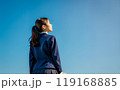 青空と学校の制服を着た女の子の後姿。 119168885