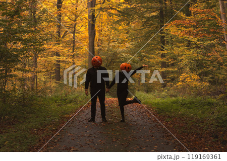 Couple in Pumpkin Heads Amidst Autumn Forest 119169361