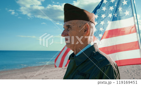 United States Veteran Looks At The Ocean From The Beach With America Flag United States Veteran Looks At The Ocean From The Beach With America Flag 119169451