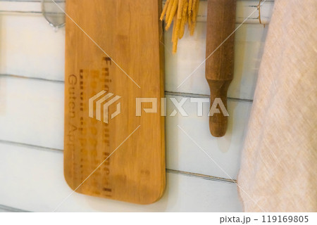 Crafted wooden kitchen utensils hanging on a rustic wall in a warm, inviting cooking space 119169805